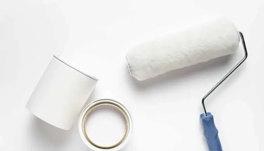 Rullo e barattolo di pittura bianca pronti per dipingere su pittura al quarzo.
