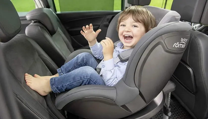 Uśmiechnięty chłopiec w foteliku samochodowym Britax Römer.