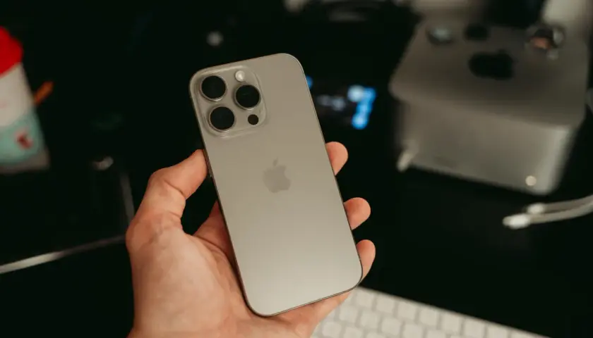 Dłoń trzyma nowy iPhone 16 ultramaryna. Z tyłu widoczny moduł aparatów i logo Apple.