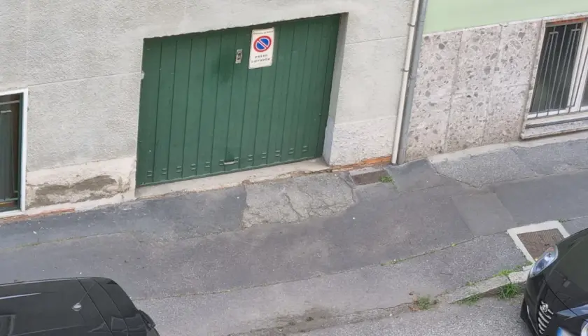 Porta garage verde con cartello "passo carrabile". Spazio di manovra libero.