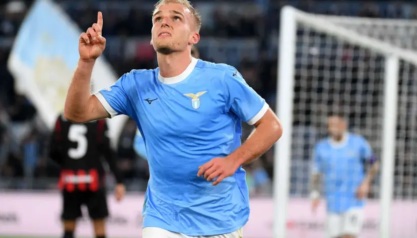 Piłkarz Lazio w błękitnej koszulce z uniesionym palcem, radośnie świętuje bramkę w meczu z A.C. Milan.