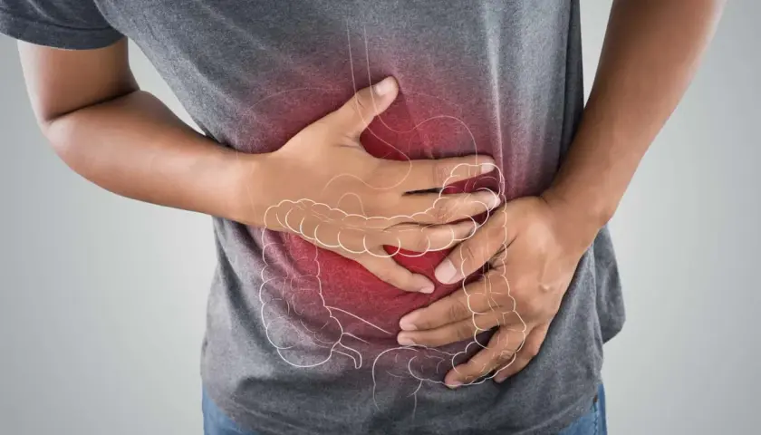 Uomo con mani sull'addome, evidenziato da un'area rossa e un contorno stilizzato dell'intestino. Potrebbe cercare rimedi per la cattiva digestione.