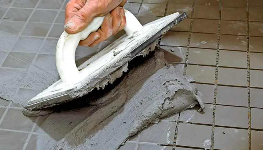 Hand spreading cement with a trowel to foga om kakel.