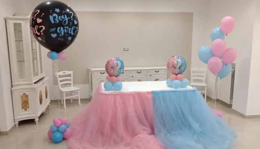 Un allestimento per un baby shower con palloncini rosa e azzurri, che simboleggiano il significato di "boy or girl?".