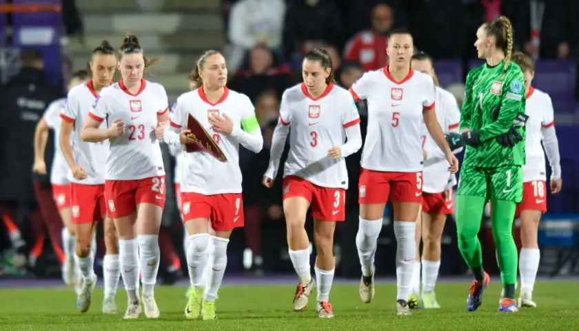 Piłkarki w biało-czerwonych strojach, dumny klub wybitnego reprezentanta, maszerują po murawie.