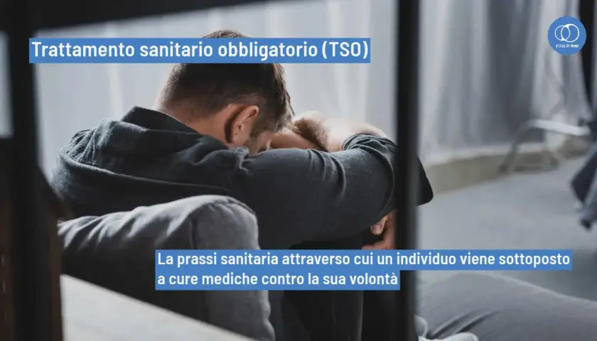 Uomo seduto con la testa tra le braccia, simbolo di sofferenza. Il TSO, trattamento sanitario obbligatorio, è una prassi medica imposta.