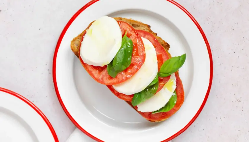 Tosta con tomate, mozzarella fresca y albahaca, inspirada en la ensalada caprese.
