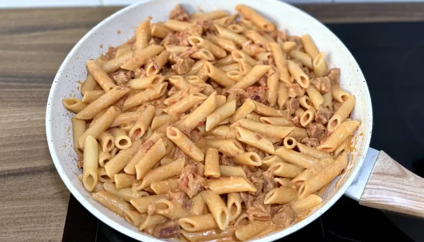 Penne z kremowym sosem i kawałkami pikantnego chorizo, przygotowane na patelni.