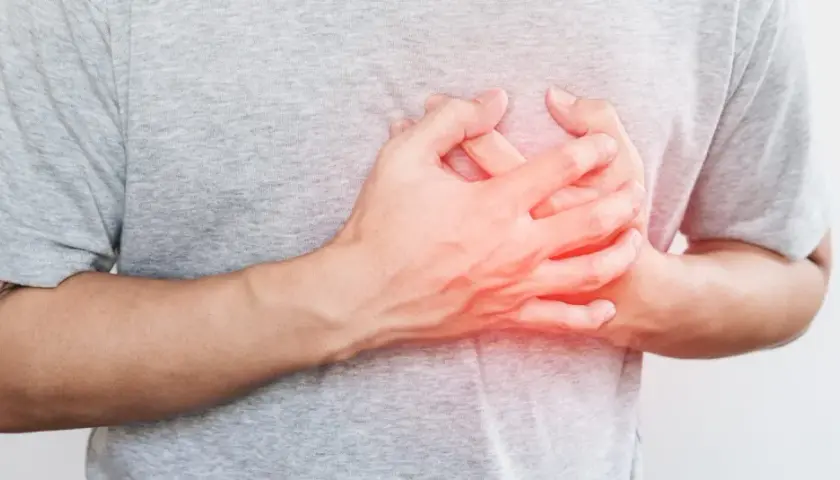 Dłoń na piersi, czerwony obszar sugeruje ból lub nierówne bicie serca.