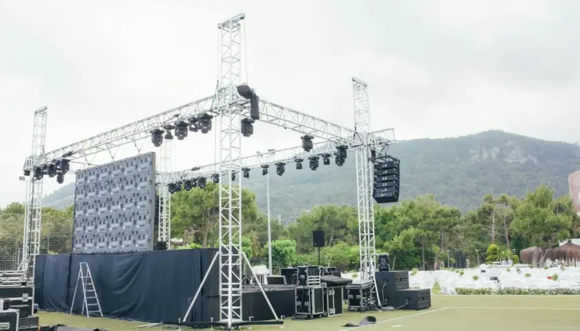 Scena z ekranem LED i różnymi rodzajami oświetlenia scenicznego, głośnikami i konstrukcjami aluminiowymi, gotowa na wydarzenie.