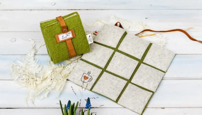 Grünes Filz-Sitzkissen mit Lederriemen und Kaffeetassen-Stickerei. Perfekt zum **sitzkissen selber machen** für gemütliche Stunden.