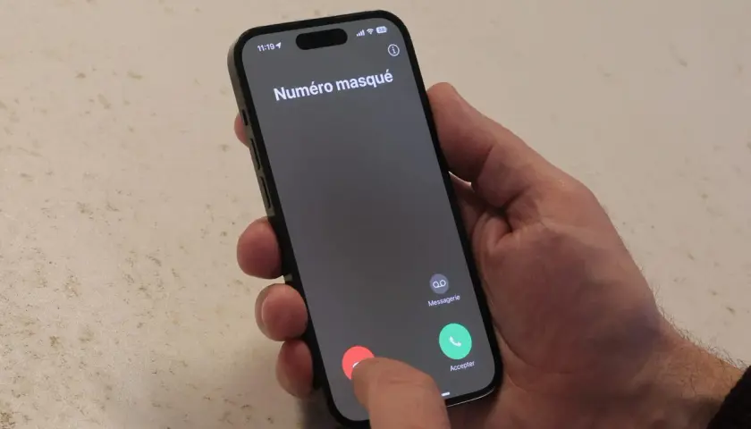 Un doigt touche le bouton rouge pour refuser un appel entrant "Numéro masqué", typique du démarchage téléphonique.