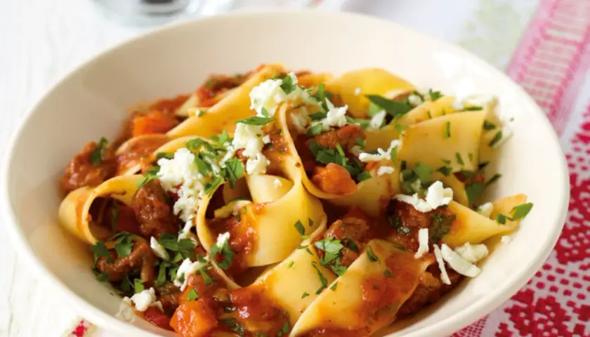 Breite Bandnudeln mit einer herzhaften Rinderhackfleischsauce und zerbröseltem Käse, ein klassisches italienisches Gericht.