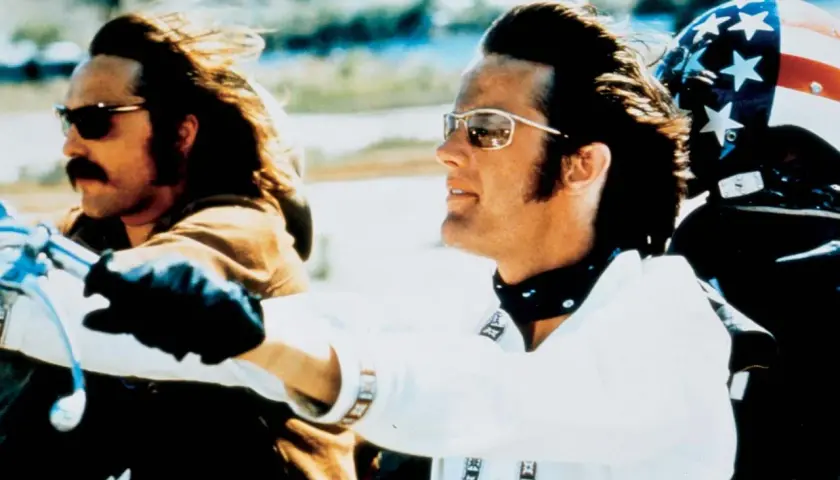 Wycieczka z rollistan i Easy Rider. Dwóch motocyklistów w okularach przeciwsłonecznych i skórzanych rękawiczkach jedzie na motocyklu.
