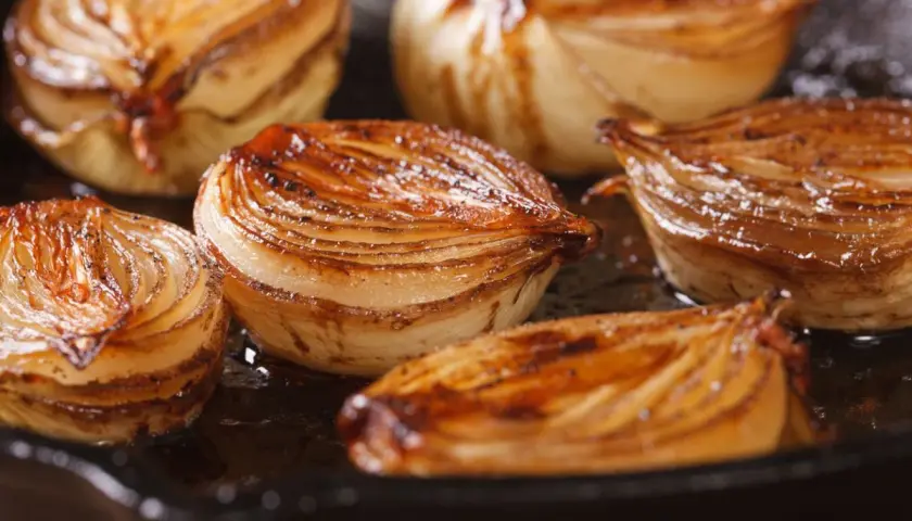 Cebolla caramelizada dorada y jugosa en una sartén.