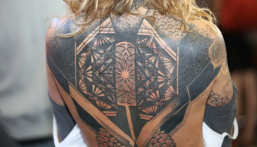Niesamowity tatuaż 3d na plecach, pełen geometrycznych wzorów i cieniowania, tworzący iluzję głębi.