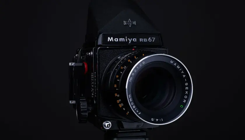 Czarny aparat Mamiya RB67 z obiektywem Mamiya-Sekor C f=180mm. Idealny do zdjęć, które wymagają precyzji i jakości, jaka klisza do aparatu jest w stanie zapewnić.