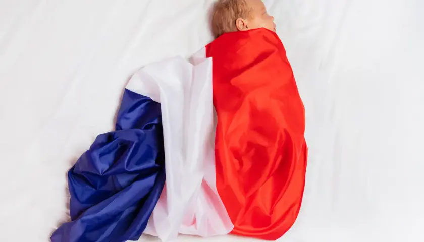 Noworodek owinięty w flagę Francji na białym tle.