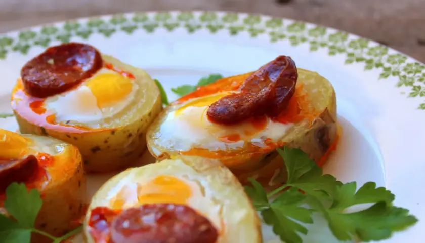 Canapés con huevo de codorniz y chorizo, horneados en rodajas de patata. Un bocado delicioso y original.