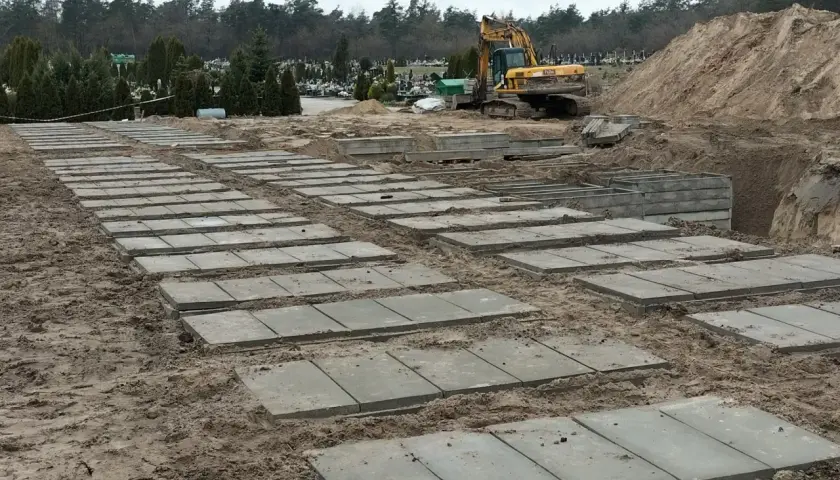Przygotowanie terenu na cmentarzu, gdzie układane są płyty betonowe. Zastanawiasz się, ile kosztuje fundament pod pomnik? Tu widać początek prac.