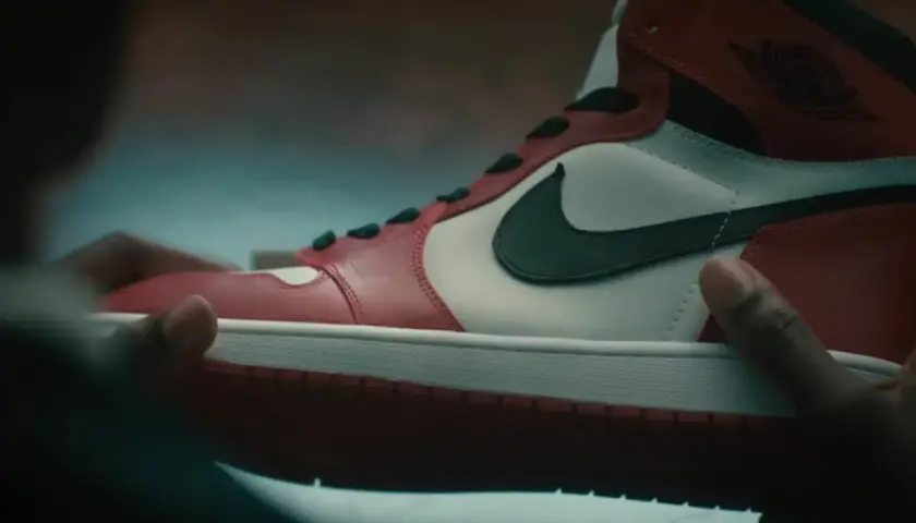 Dłonie trzymają kultowe czerwono-białe buty Air Jordan 1. Ten się śmieje, kto ma zęby, a te buty to marzenie wielu.