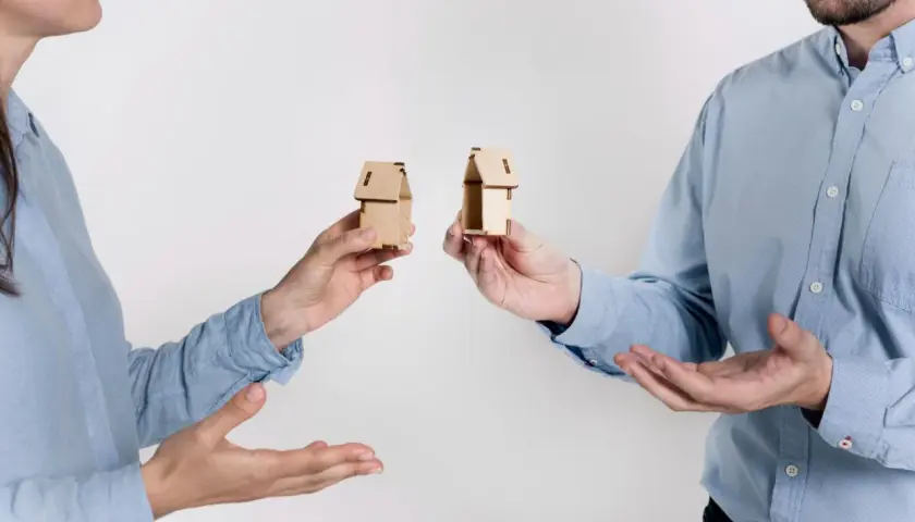 Rozdzielność majątkowa a wspólny dom: dwoje ludzi trzyma miniaturowe domki, symbolizujące podział majątku.