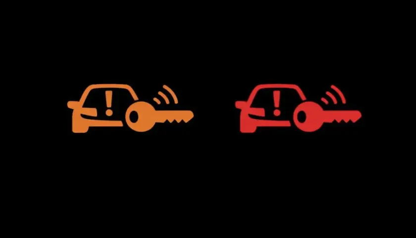 Pomarańczowa i czerwona kontrolka auto z kluczem. Sygnalizuje problem z immobilizerem lub kluczykiem.