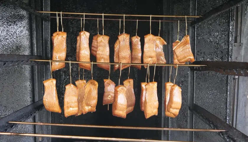 Filets de saumon suspendus dans un fumoir, prêts pour le fumage à froid. Le saumon est une excellente viande à fumer à froid.