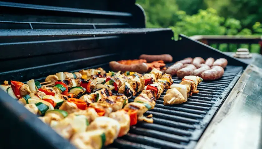 Brochettes de poulet et légumes, saucisses en train de griller sur un barbecue, parfait pour une soirée barbecue d'été.