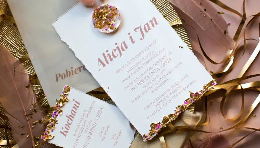 Eleganckie zaproszenia ślubne z ozdobnymi piórami i złotymi elementami.