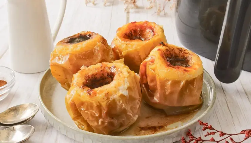 Cuatro deliciosas manzanas asadas en freidora de aire, con un relleno dulce y especiado, listas para disfrutar.