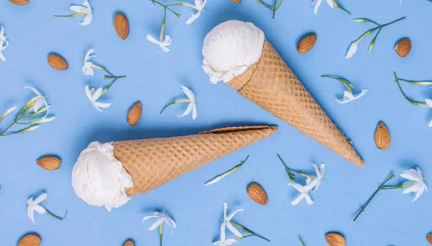 Due coni gelato al gelsomino, circondati da mandorle e delicati fiori bianchi su sfondo azzurro.