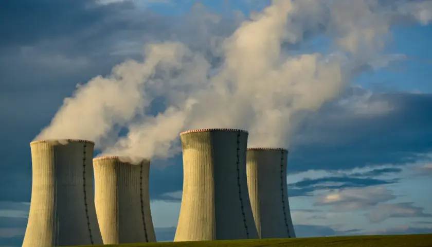 Chłodnie kominowe elektrowni jądrowej na tle burzowego nieba. Czy energia jądrowa jest ekologiczna? Dym unoszący się z kominów budzi pytania.