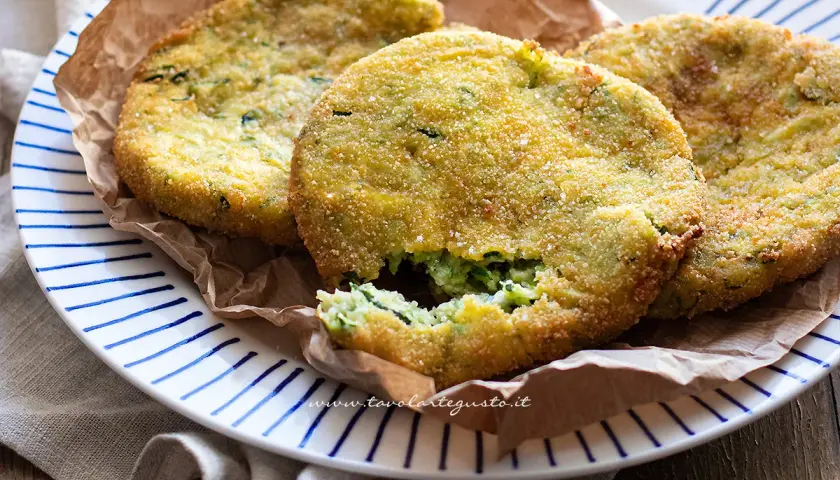 Crocchette di zucchine al forno, dorate e croccanti, servite su un piatto a righe blu.