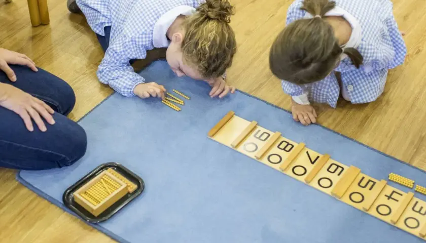 Niñas aprendiendo con el método Montessori en colegios, usando cuentas para sumar.