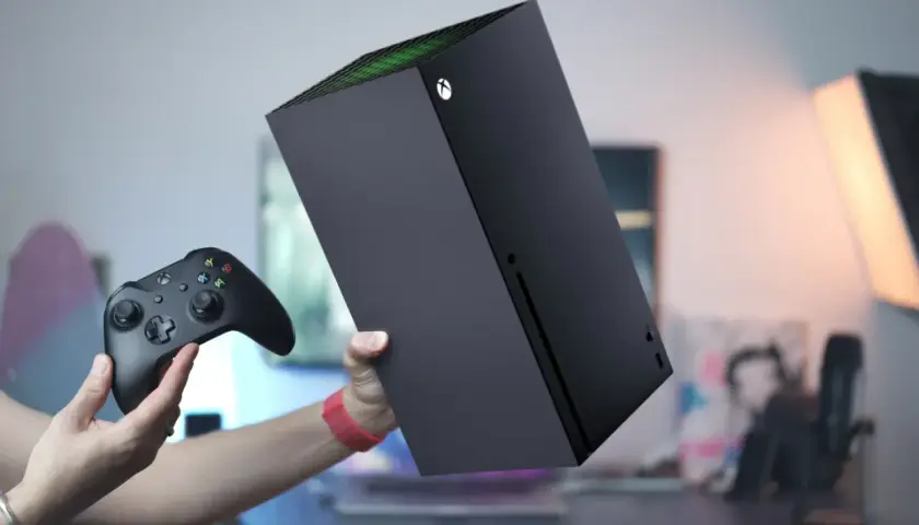 Ręce trzymają czarny kontroler Xbox i konsolę Xbox Series S. Dowiedz się, jak podłączyć drugiego pada do Xbox Series S.