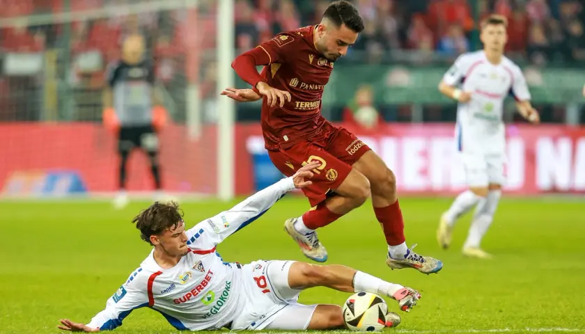 Piłkarz Widzewa Łódź walczy o piłkę z zawodnikiem Górnika Zabrze. Intensywna akcja na boisku.
