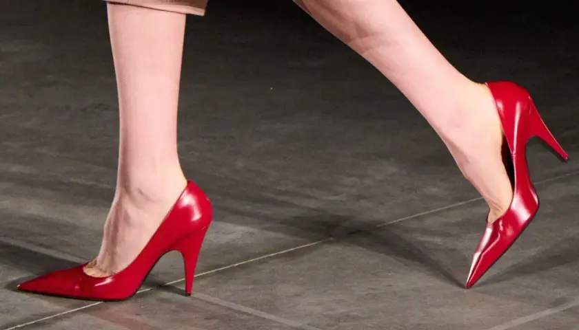 Pieds chaussés de talons aiguilles rouges brillants, symbolisant la confiance et le pouvoir.