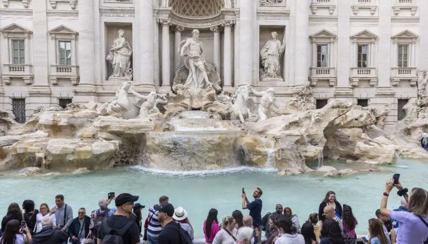 La fontaine de Trevi, avec ses statues majestueuses et ses chevaux marins, attire une foule de visiteurs capturant ce moment magique avec leurs téléphones.