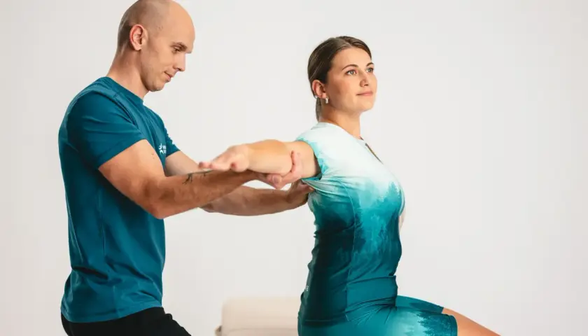Fizjoterapeuta pomaga pacjentce w rehabilitacji ręki po złamaniu kości promieniowej, wykonując ćwiczenia zakresu ruchu.