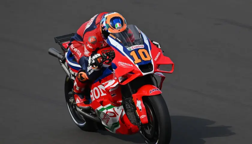 Luca Marini en su moto Honda número 10, con su traje rojo y azul, compite en la pista.