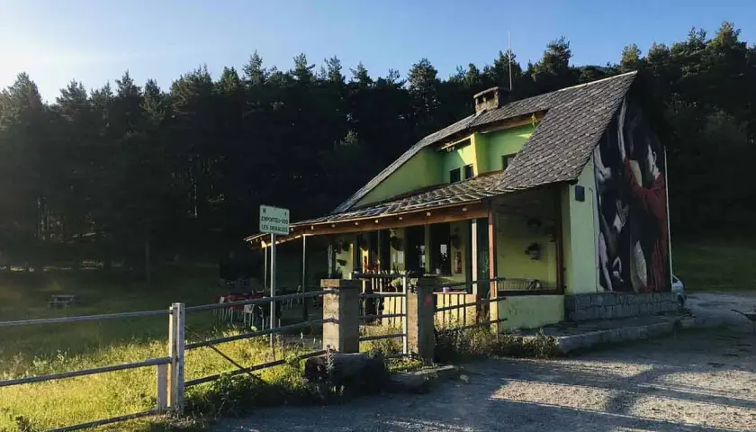 El refugi Serrat de les Esposes, un refugio acogedor rodeado de pinos, con un mural artístico en su fachada.