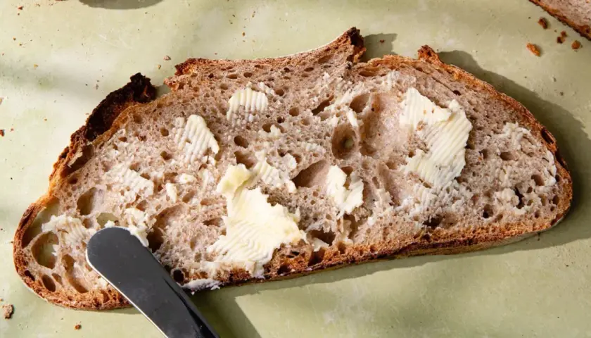 Tranche de pain de campagne, généreusement beurrée, prête à être dégustée. Une invitation à la simplicité et au bon goût.