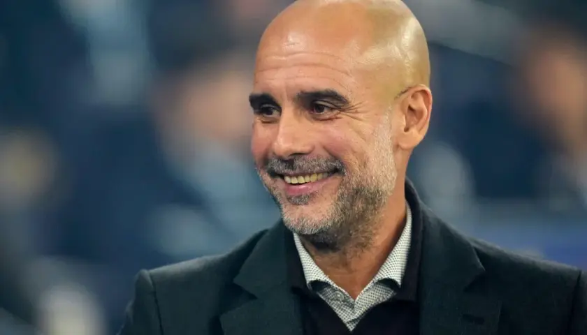 Uśmiechnięty Pep Guardiola, trener Manchesteru City, omawia najnowsze manchester city transfery.