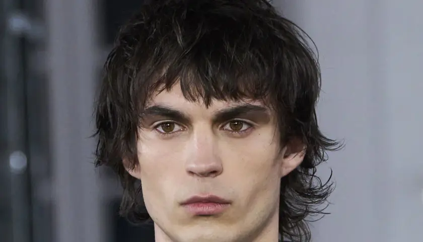 Hombre con un moderno mullet de pelo corto, mirada intensa y cejas marcadas.