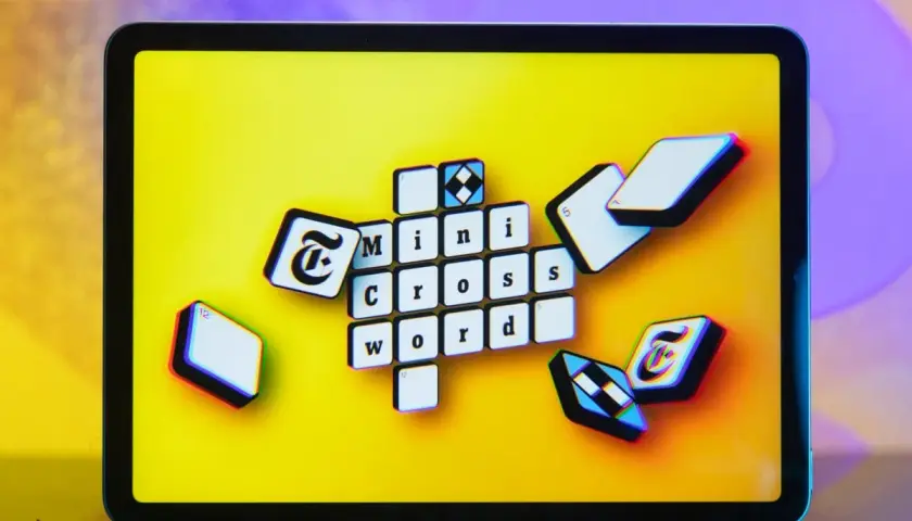 Pomoc krzyżówkowicza z przymrużeniem oka: litery "Mini Cross Word" na ekranie tabletu, jakby ktoś szukał podpowiedzi.
