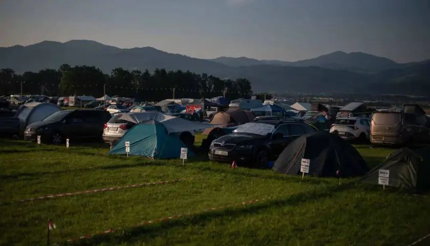Rozległe pola namiotowe Austria, pełne namiotów i samochodów, z górami w tle.