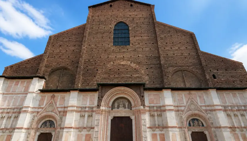 Façade imposante de la basilique San Petronio, mélange de briques rouges et de marbre blanc, sous un ciel bleu.