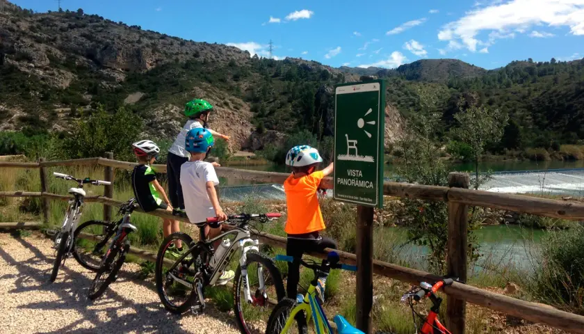 Niños en bicicleta disfrutan de la **vía verde Val de Zafán**, señalizada con un mirador panorámico.