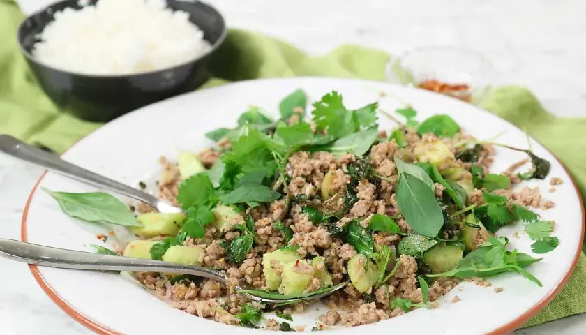 En tallrik med en smakrik larb-rätt, toppad med färska örter och serverad med ris. Ett perfekt larb recept för en snabb och god middag.
